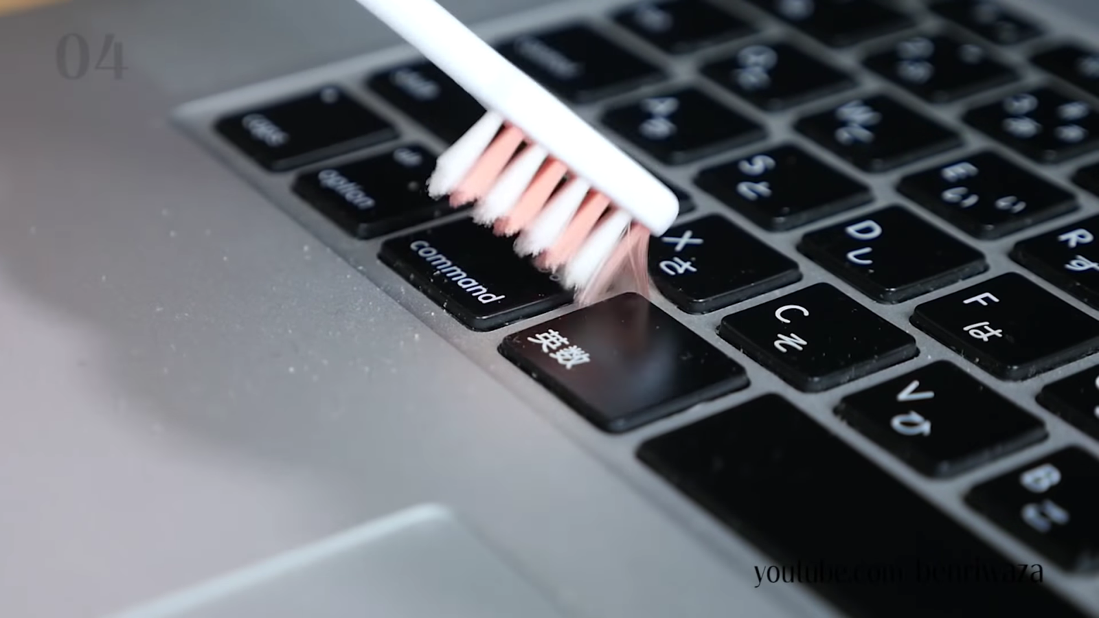 歯ブラシでパソコンの汚れを取る男性