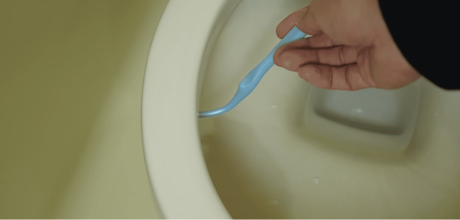 歯ブラシでトイレ掃除をする男性