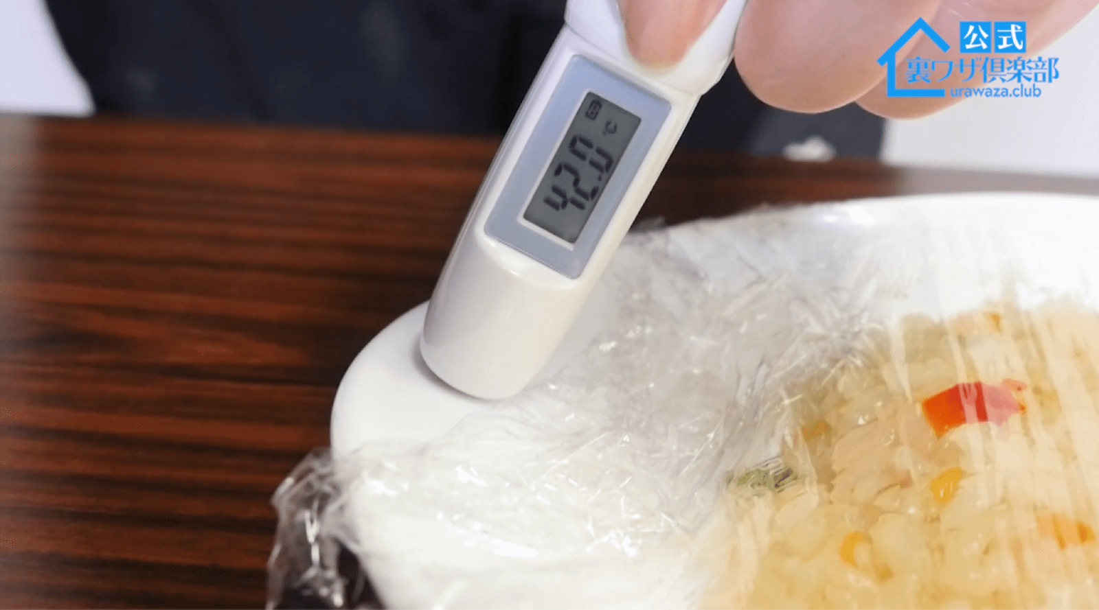 レンジで加熱したラップの温度を測る女性