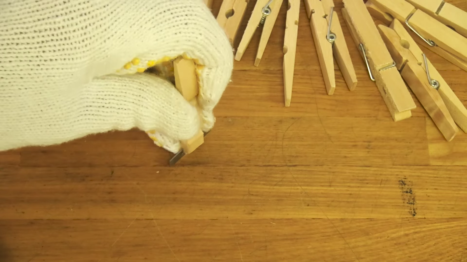 木製クリップに鉛筆削りの刃を入れる男性