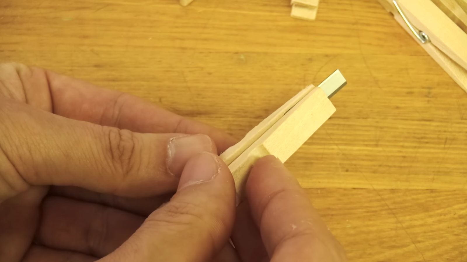 木製クリップに鉛筆削りの刃を付ける男性