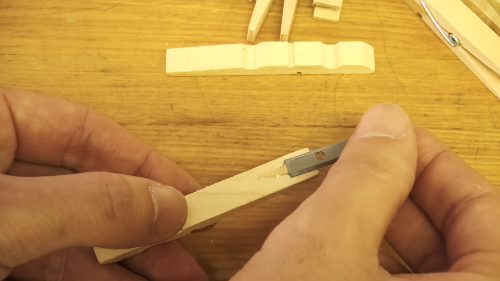 木製クリップに鉛筆削りの刃を付ける男性