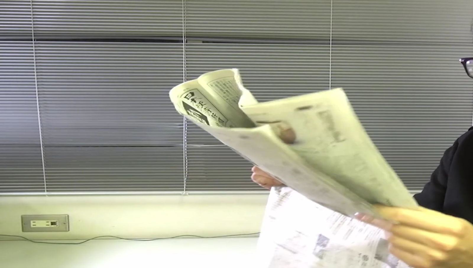 新聞を折り曲げる男性