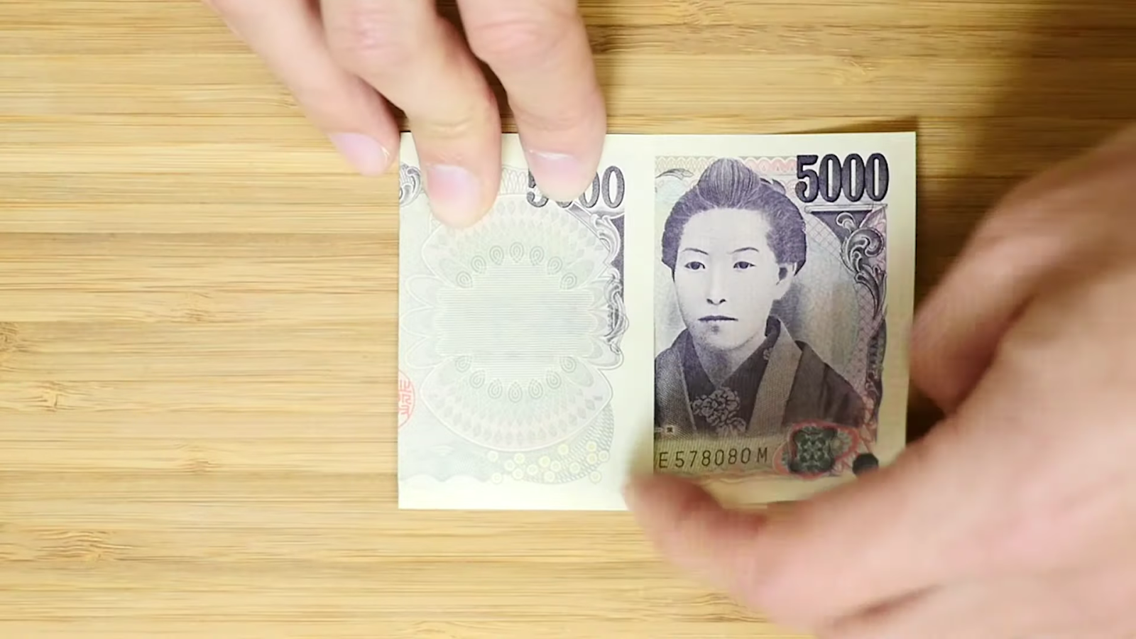 五千円札を折る男性
