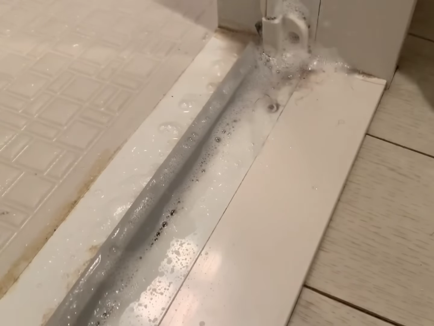 お風呂場の扉下を掃除する男性