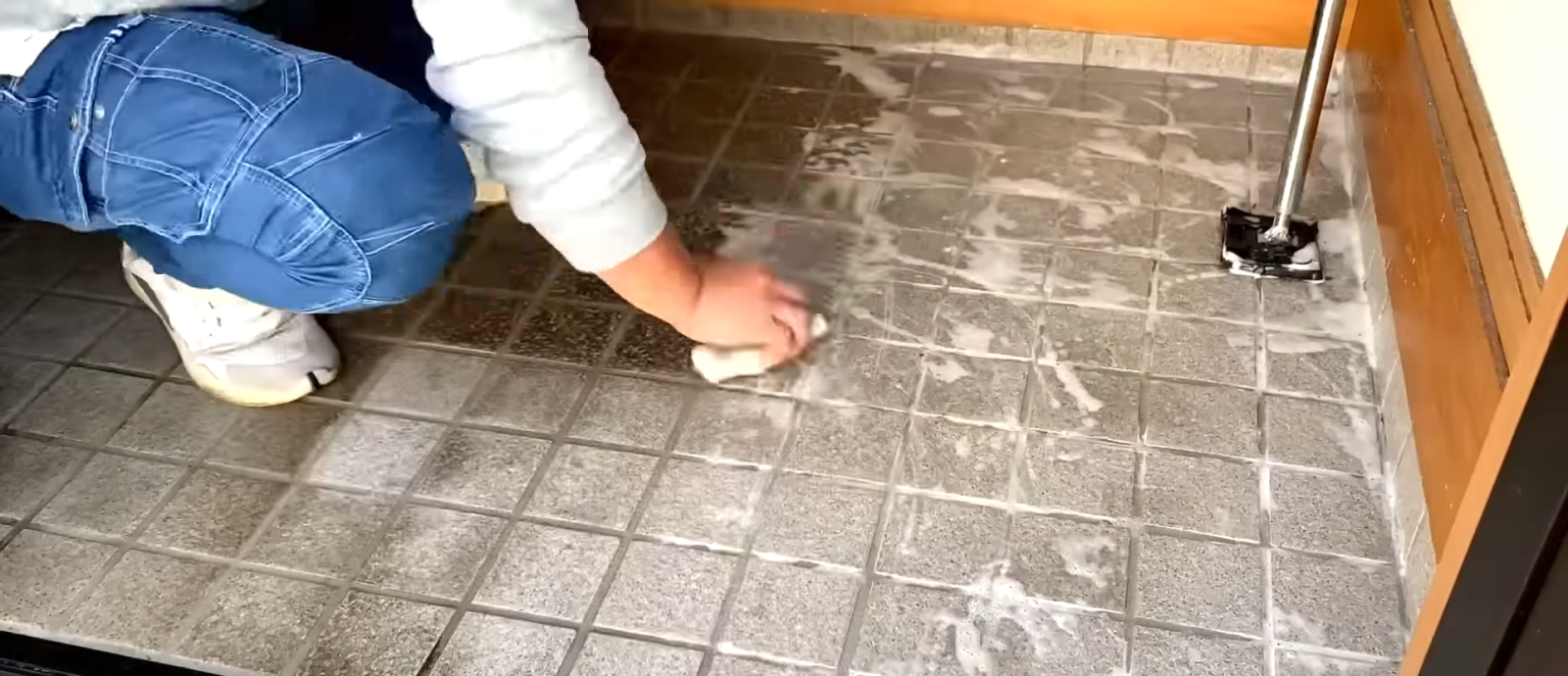 玄関の床掃除をする男性