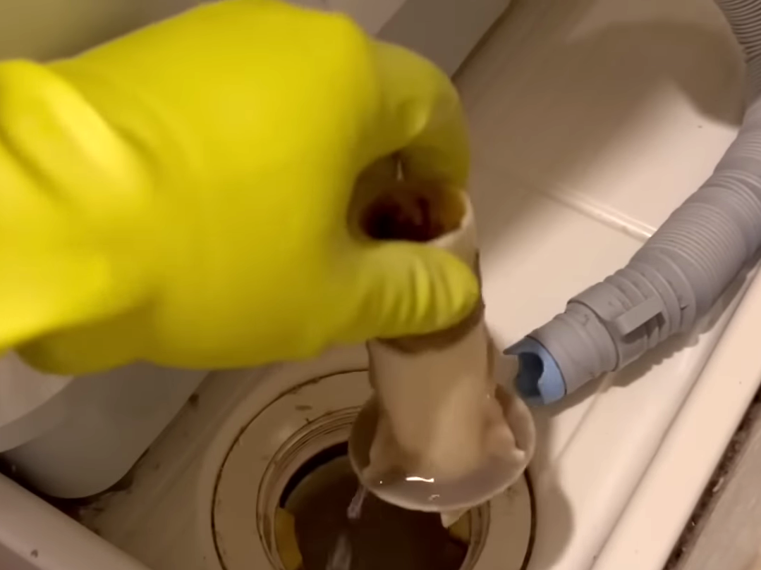 洗濯機の排水口を掃除する男性