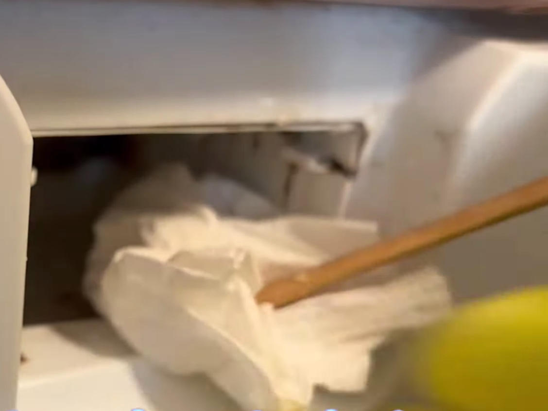 キッチンペーパーと割り箸で掃除をする男性