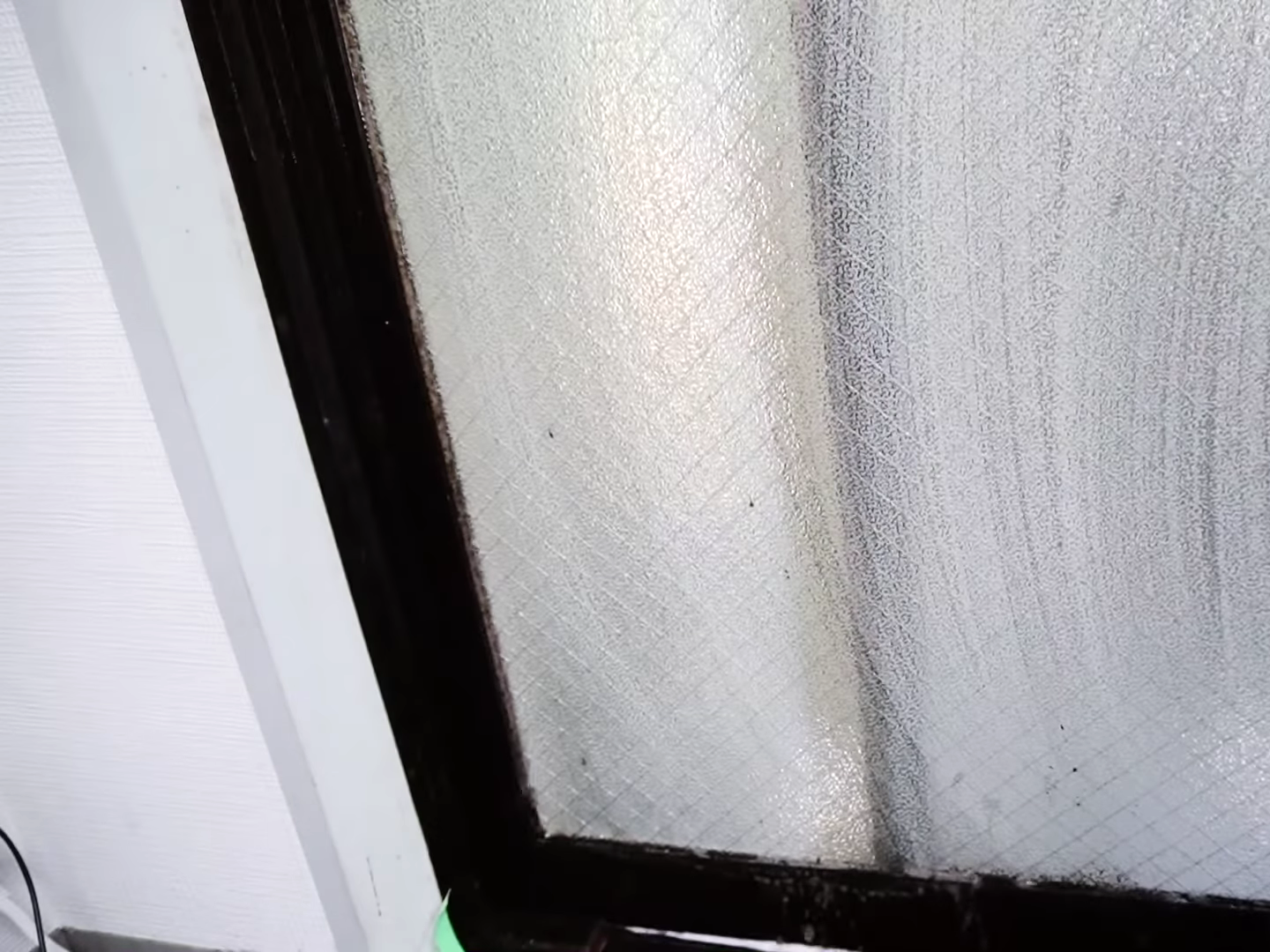 カビが生えた窓を掃除する男性