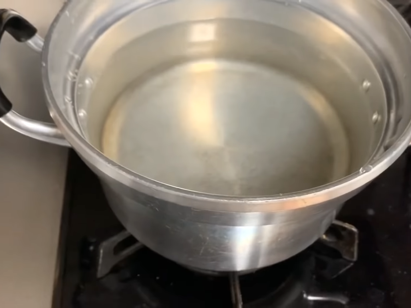 鍋にいれた水を沸騰させる男性