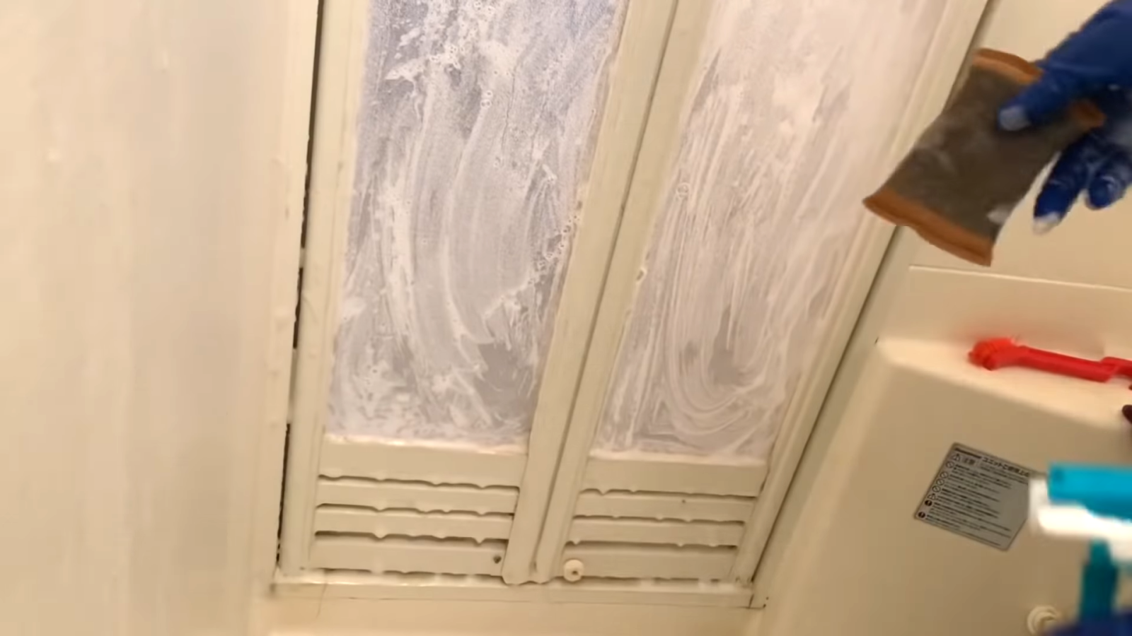 お風呂場の扉に洗剤を吹きかける男性
