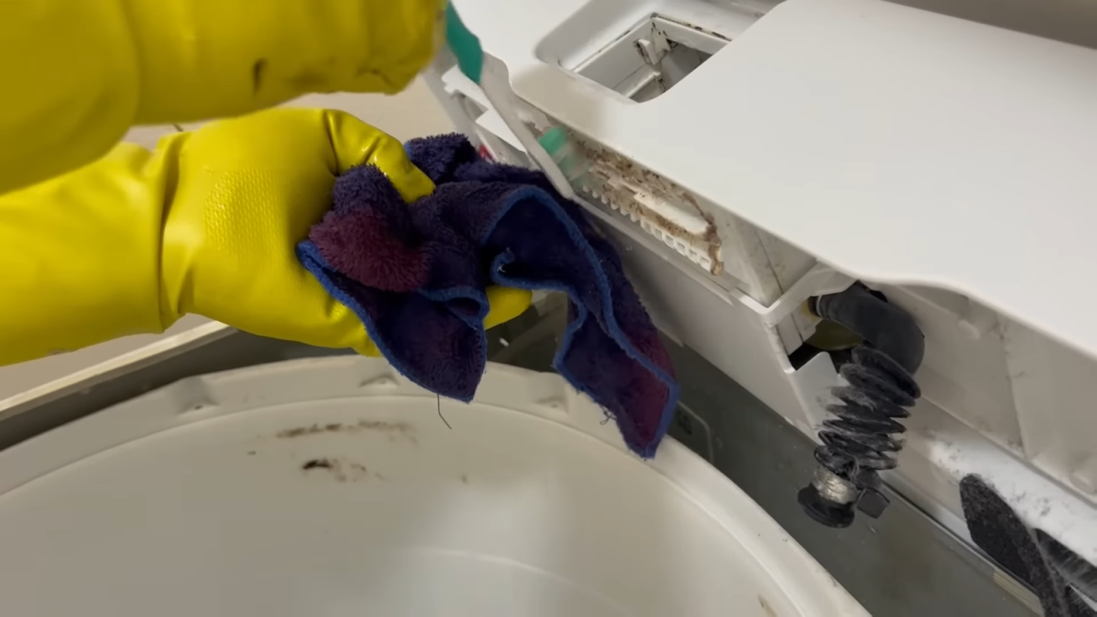 洗剤をつけたタオルで洗濯機を掃除する男性