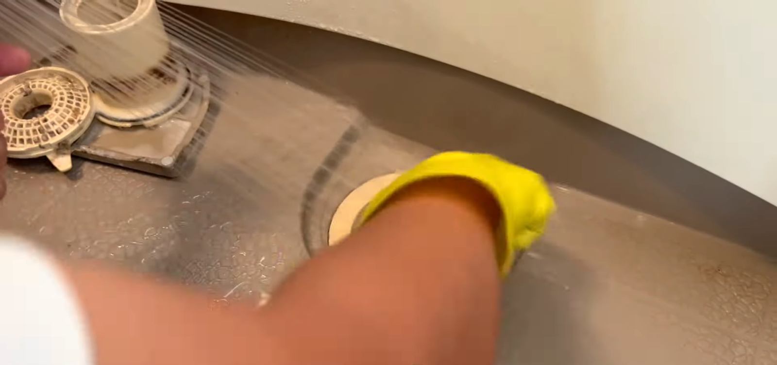 浴室の排水口の汚れをブラシで取る男性
