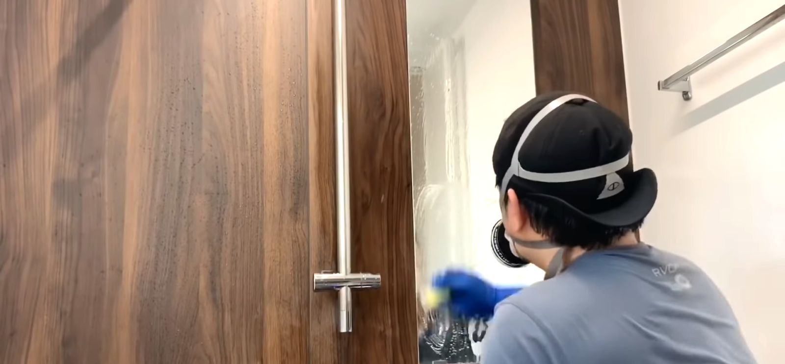 鏡についた水垢を掃除する男性