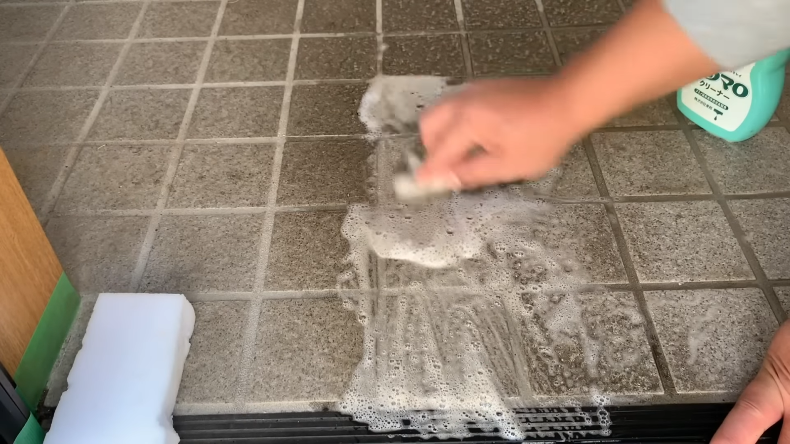 メラミンスポンジと洗剤で玄関を掃除する男性