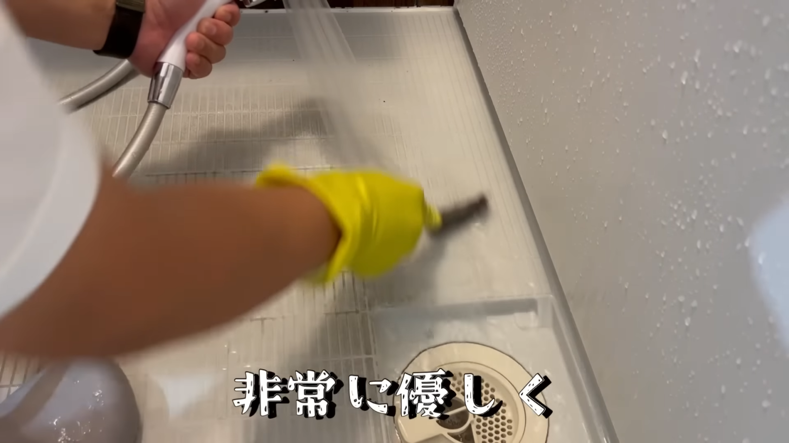 ステンレス製のチャンネルブラシでお風呂場の床を掃除する男性