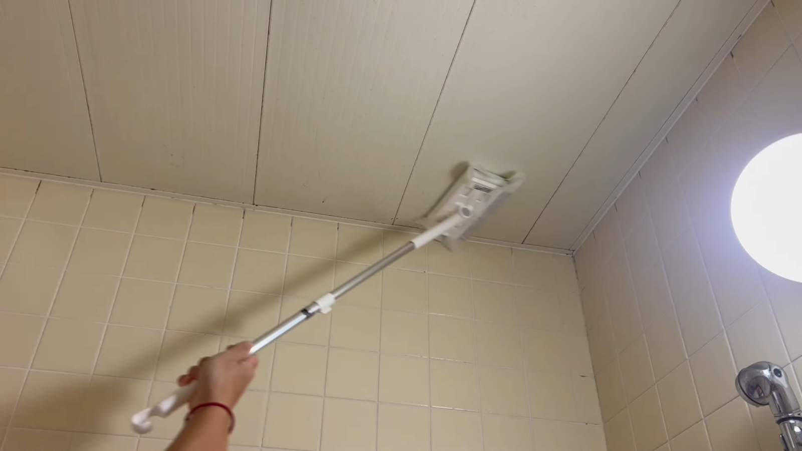 浴室の天井を掃除する男性