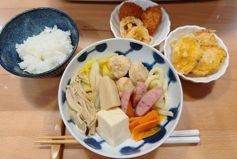 寄せ鍋と天ぷらなどの揚げ物が並んだ食卓