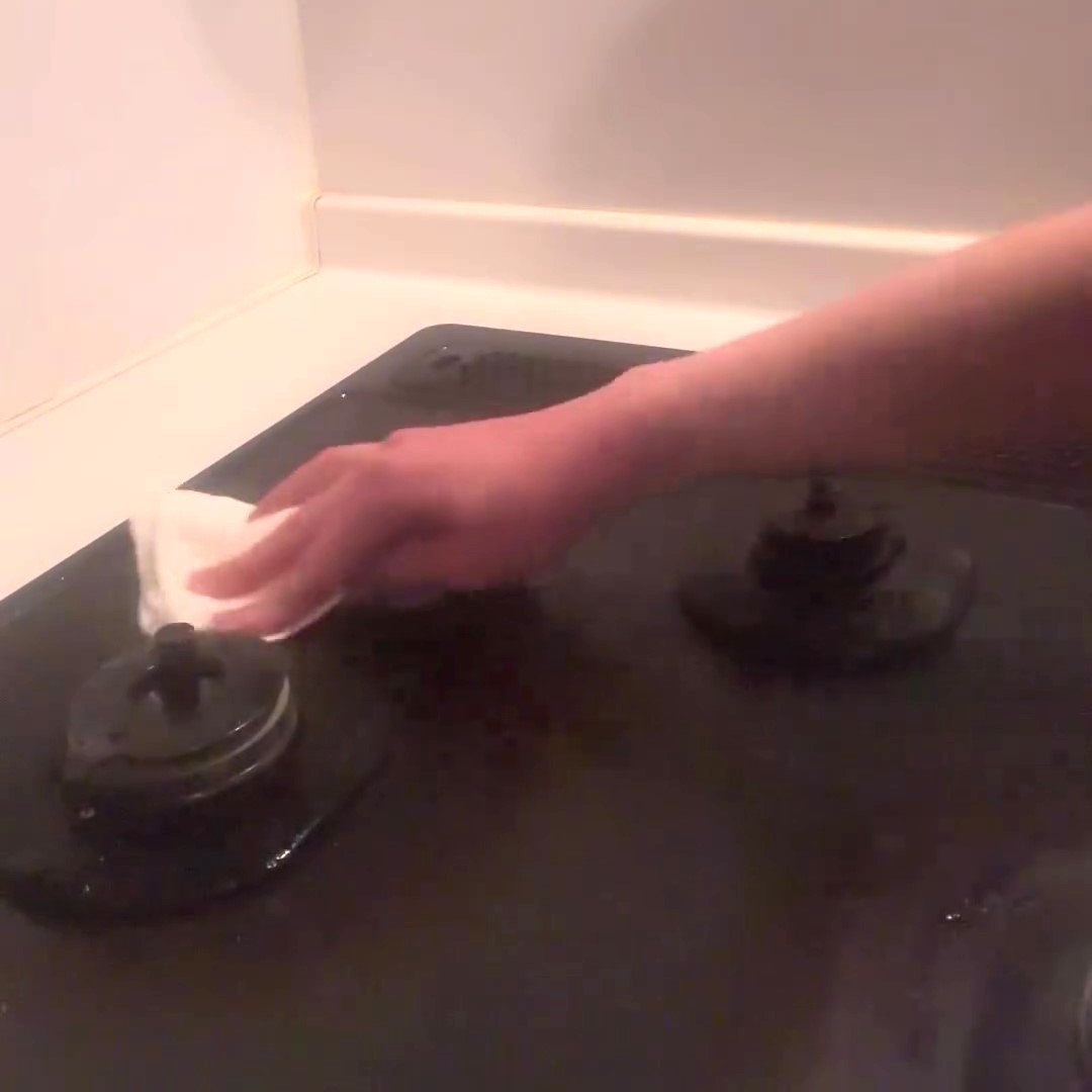 アルカリ電解水でキッチンの油汚れを拭き取る女性