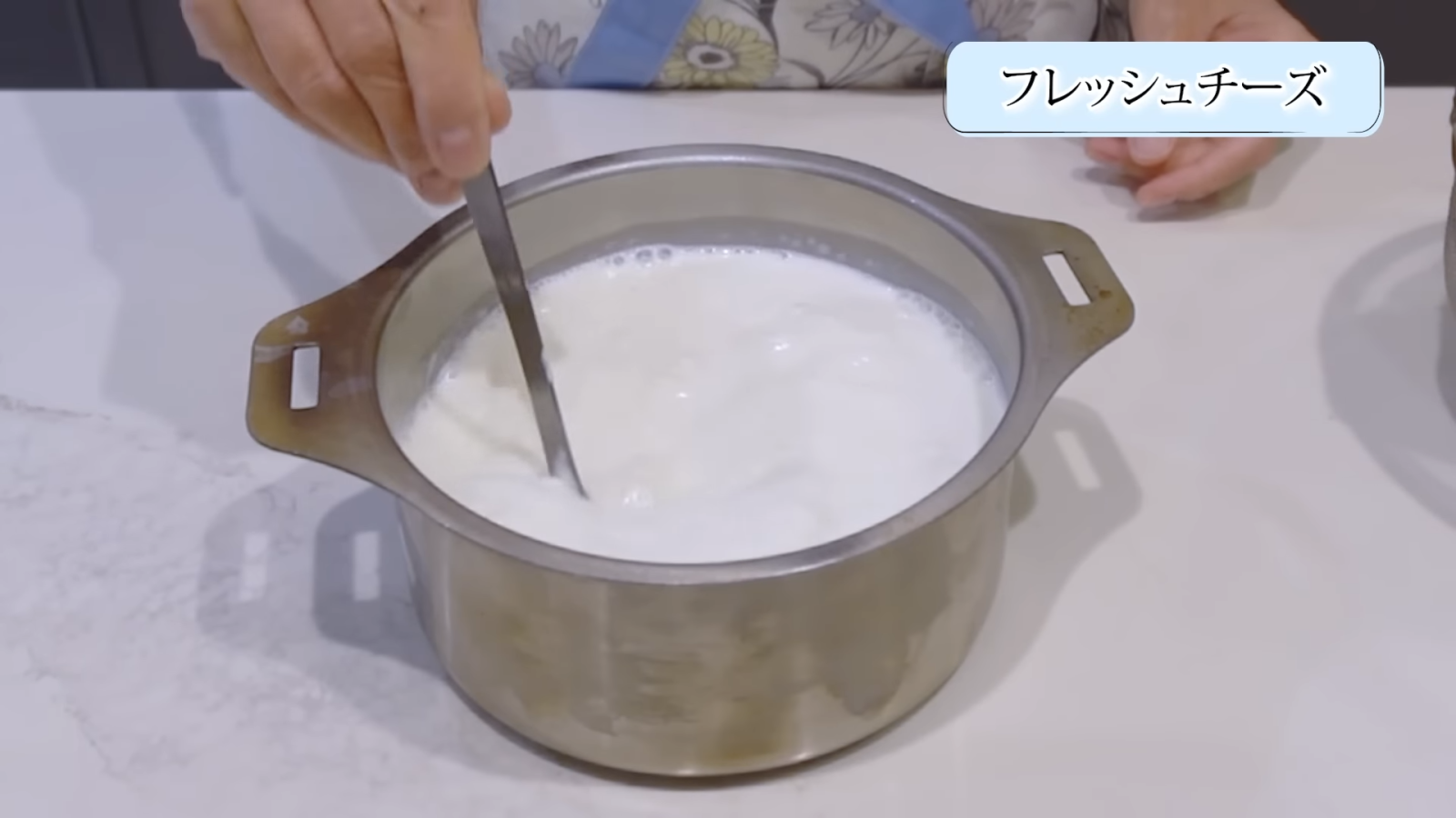 鍋に入れた牛乳とプレーンヨーグルトを混ぜ合わせる女性