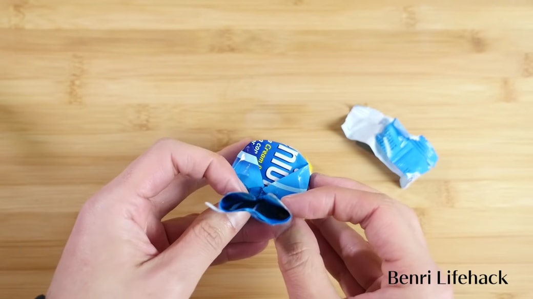 筒状のお菓子袋を閉じる男性