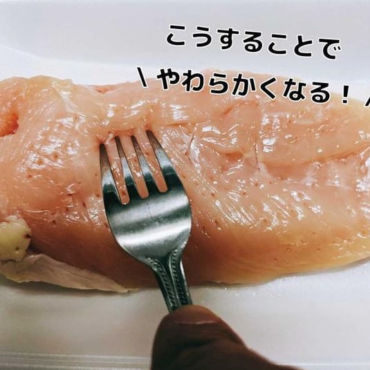 鶏むね肉をフォークで刺す男性