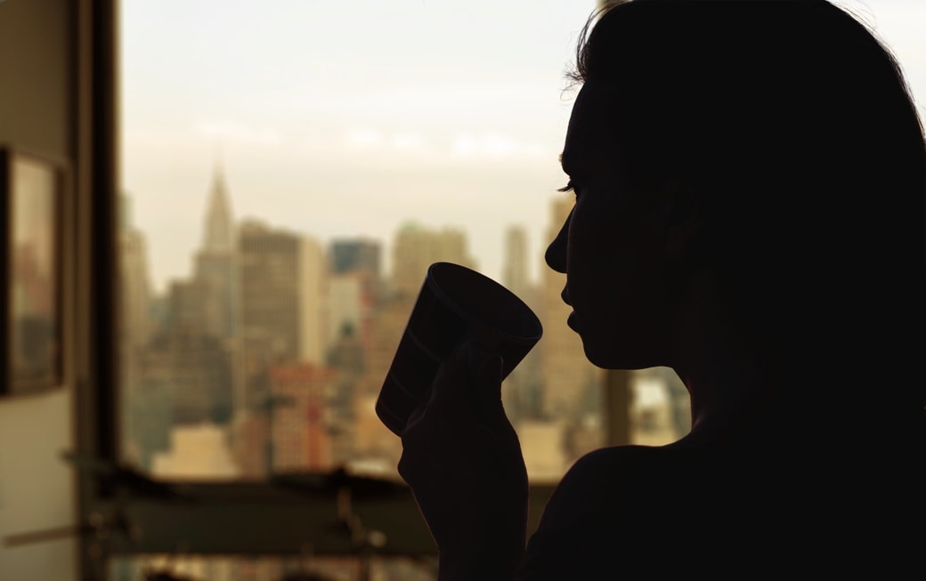 高層ビルにコーヒーを飲む女性