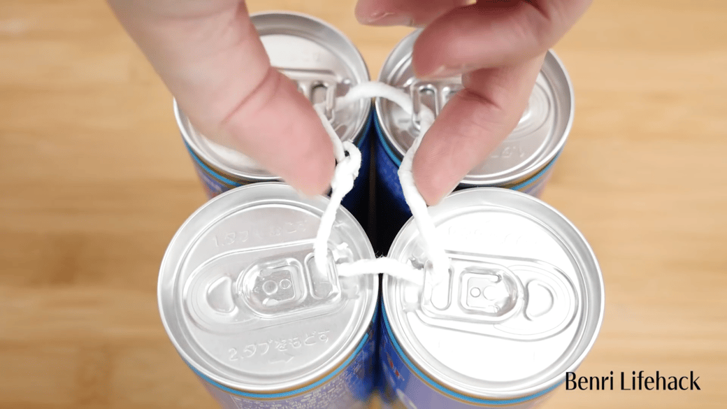 こよりを使って缶をまとめて持つ男性
