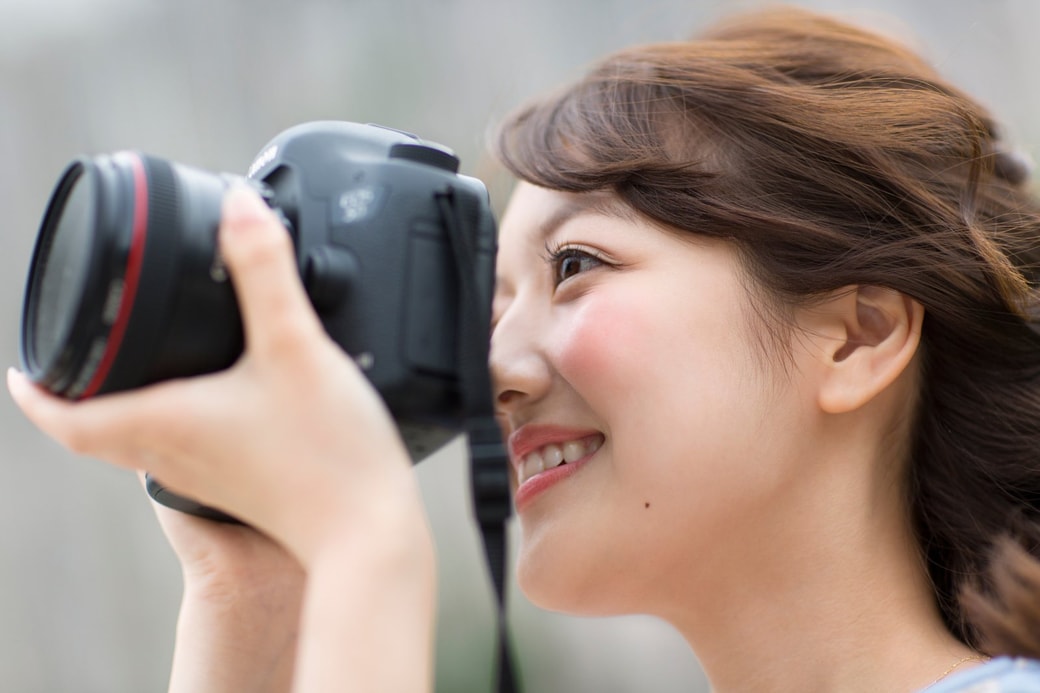 カメラのレンズを覗く女性