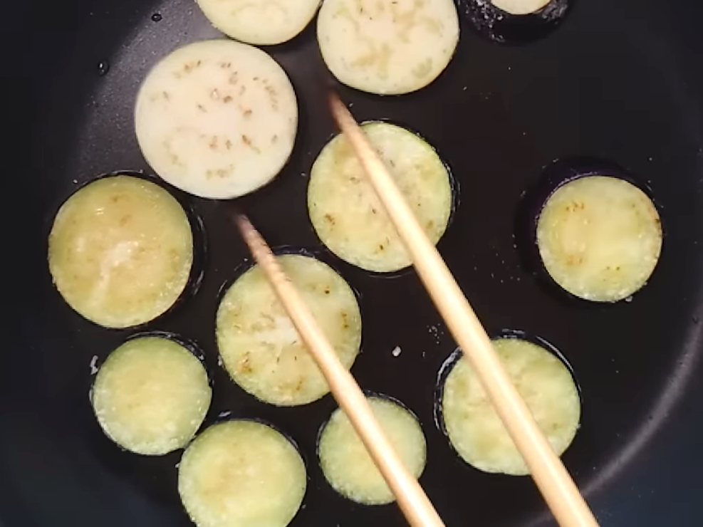 フライパンでナスを焼いている人