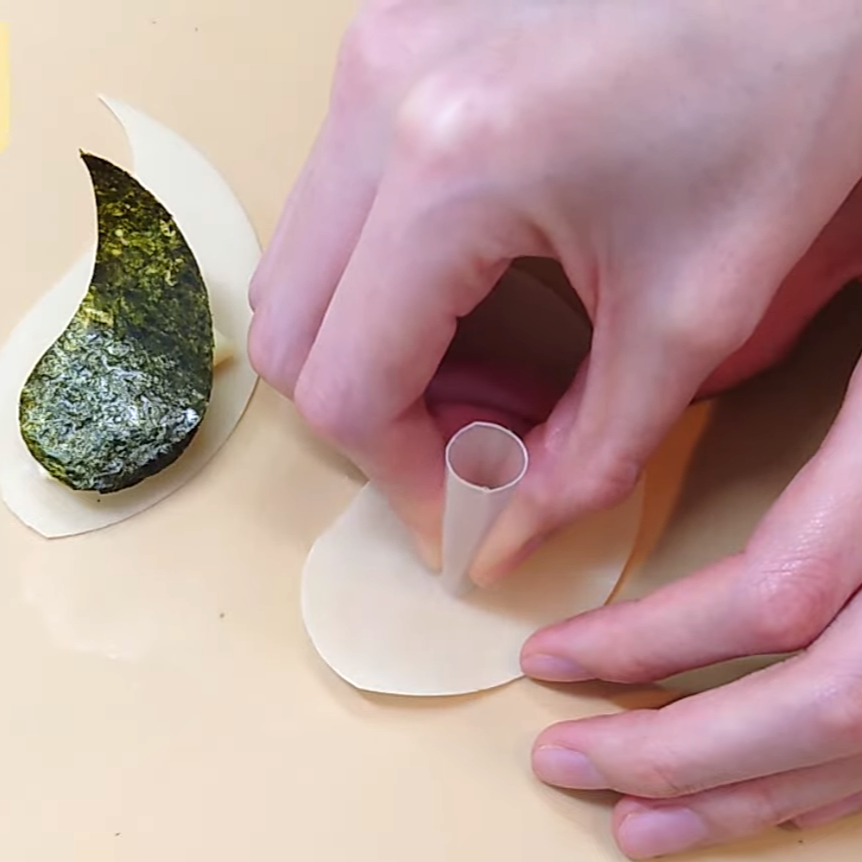 ストローで餃子の皮に顔を作る女性