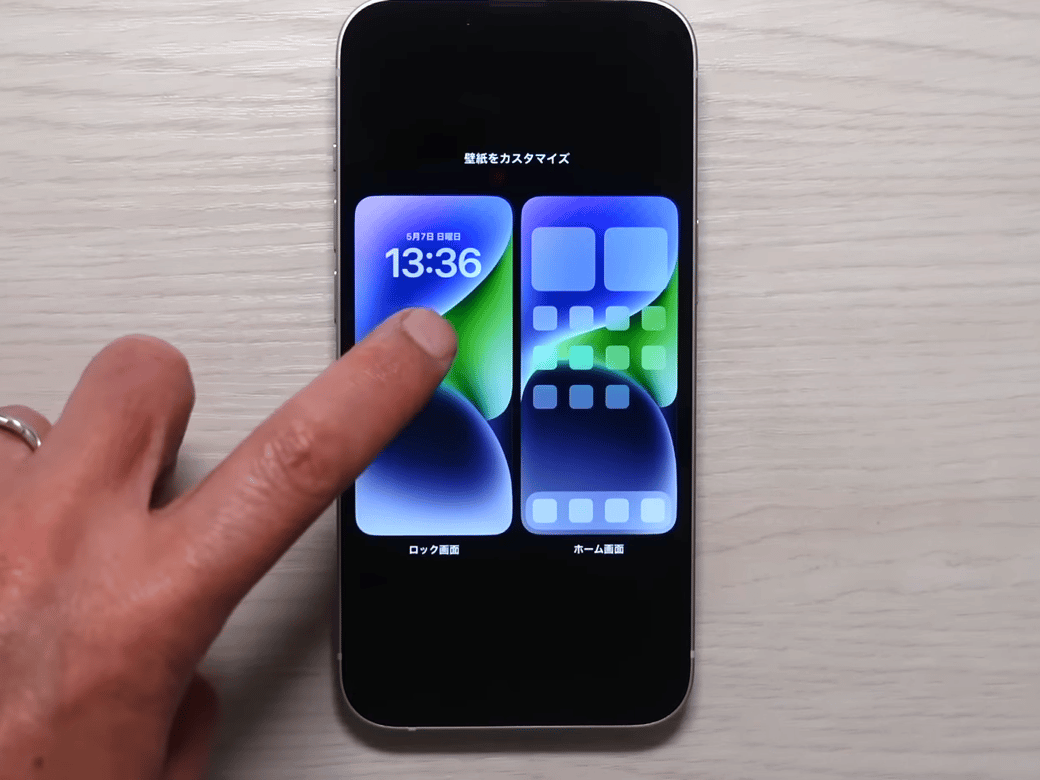 iPhoneのカスタマイズからロック画面をタップする男性