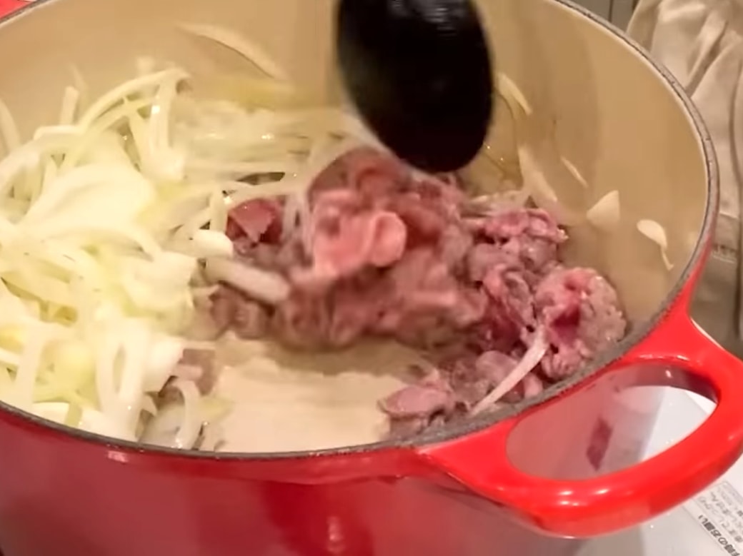 鍋で玉ねぎや牛肉を炒める女性