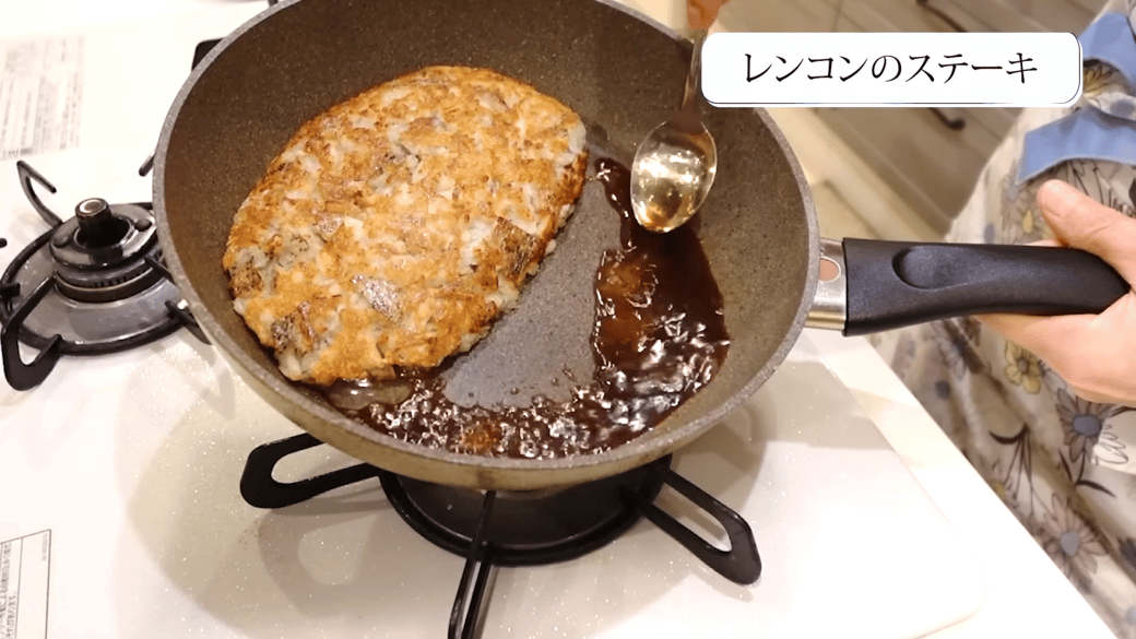 フライパンでれんこんステーキを作る女性