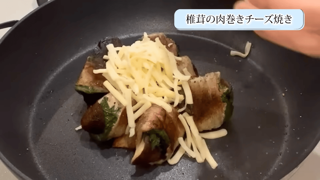 フライパンで焼いた椎茸にチーズをのせる女性