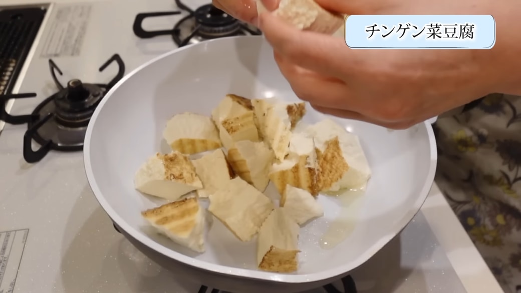 フライパンに焼き豆腐を入れる女性