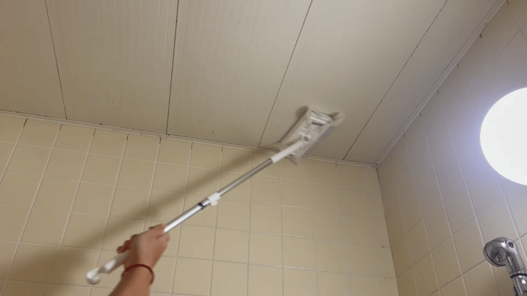 浴室の天井を掃除する男性