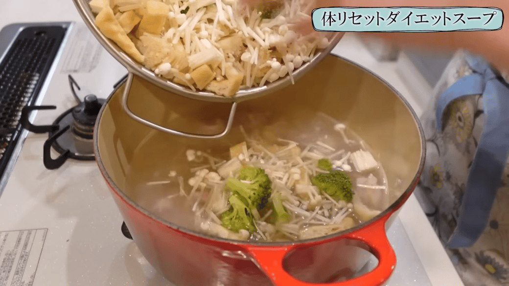 鍋にカットした野菜や油揚げを入れる女性