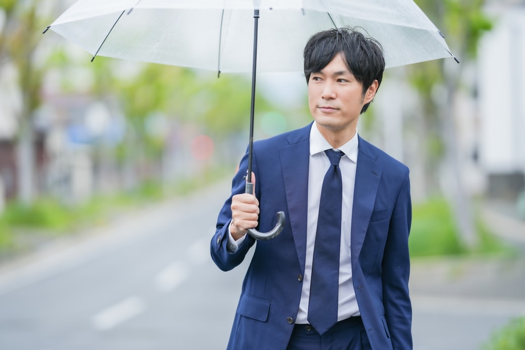 雨の中で傘をさすビジネスマン