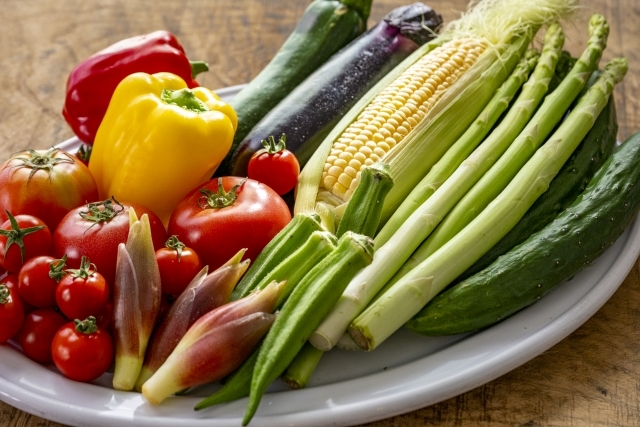 皿にのったトマトやとうもろこしなどの夏野菜