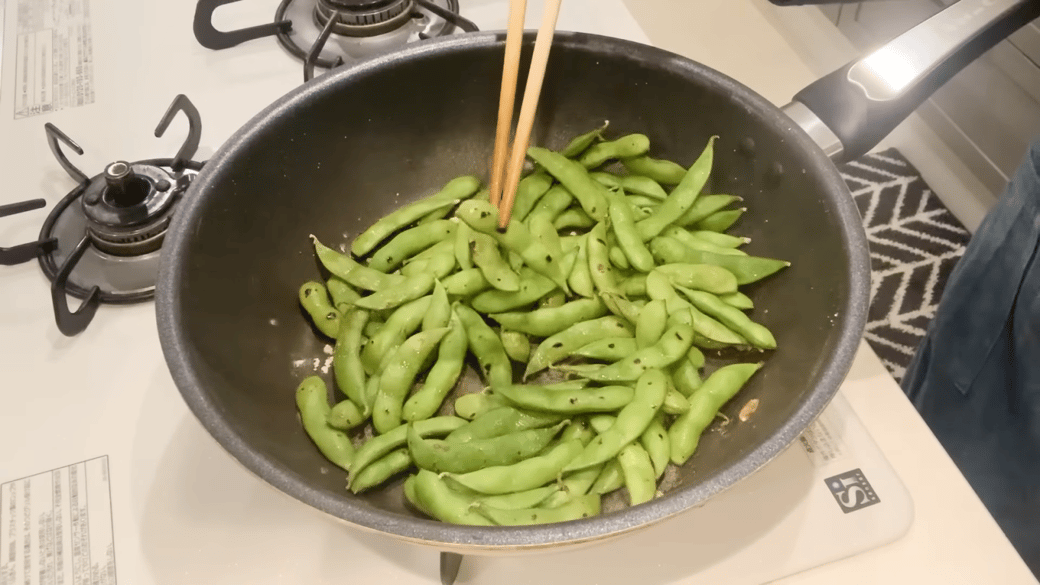 蒸し焼きにした枝豆を菜箸で持つ女性