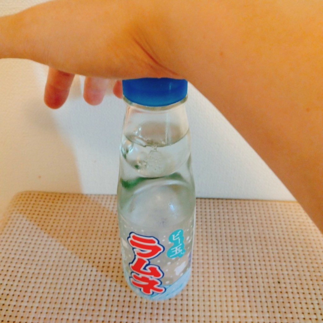 玉押しを使って瓶のラムネを開ける人