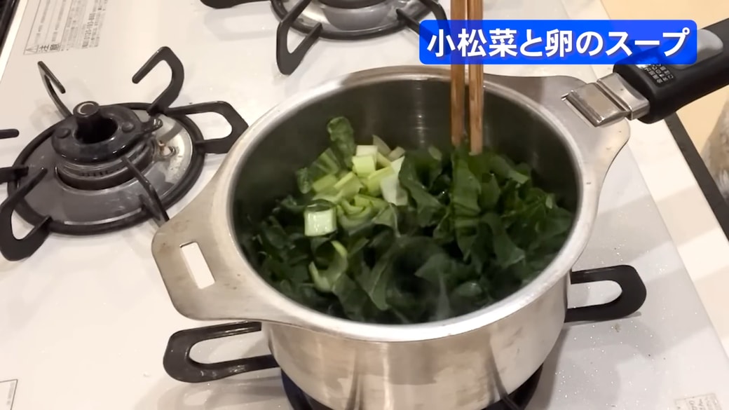 鍋で小松菜を炒める女性