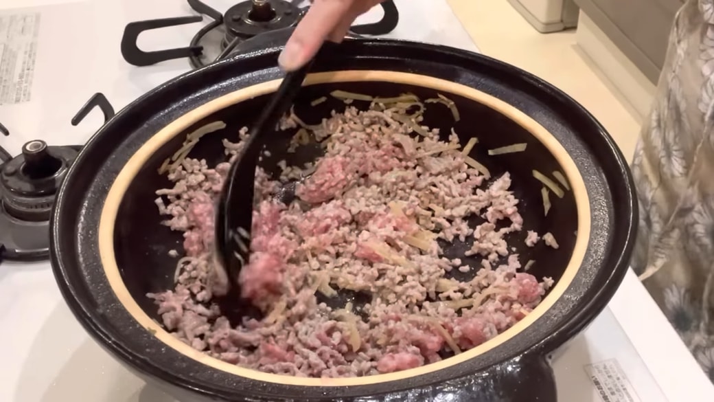 鍋でひき肉やしょうがを炒める人