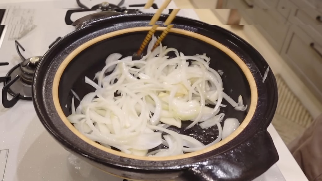 鍋でにんにくと玉ねぎを炒める人