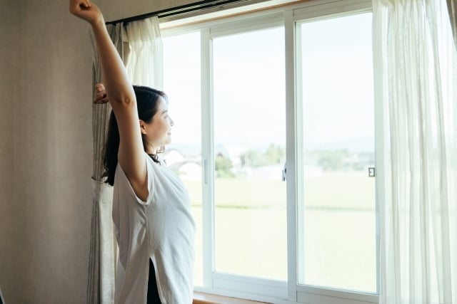 窓辺で伸びをする女性