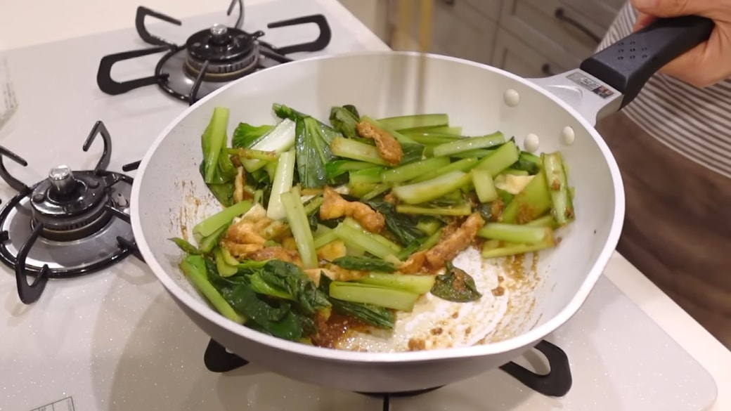 フライパンで小松菜とごま油を炒める人