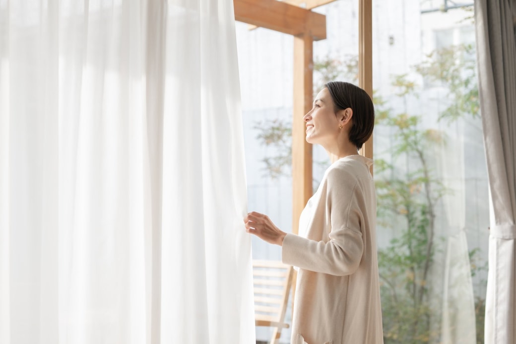 カーテンを開ける女性