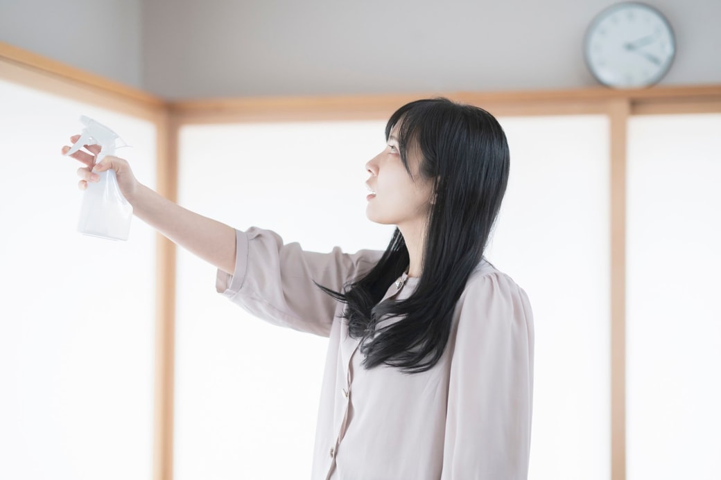 部屋にスプレーをする女性