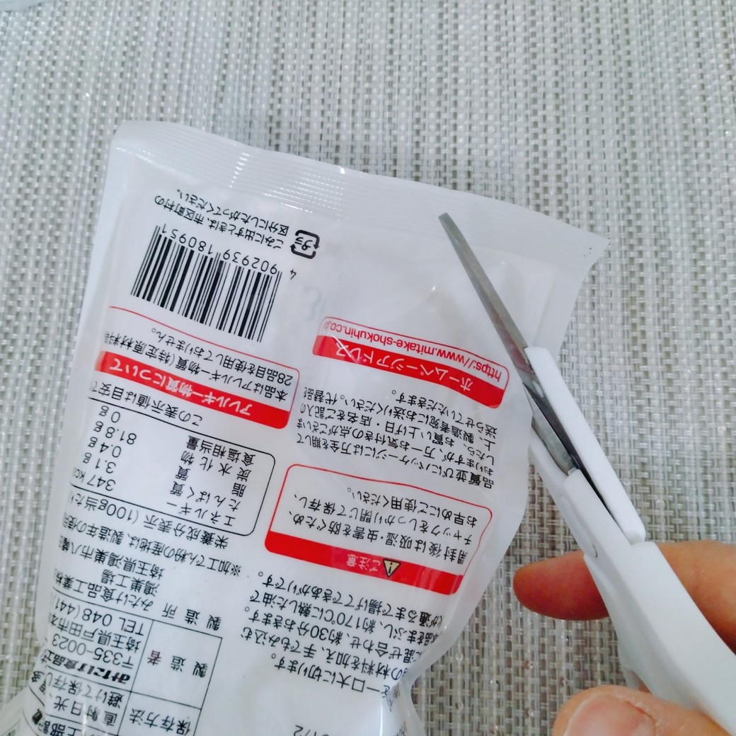 ハサミでかたくり粉が入った袋を切る人